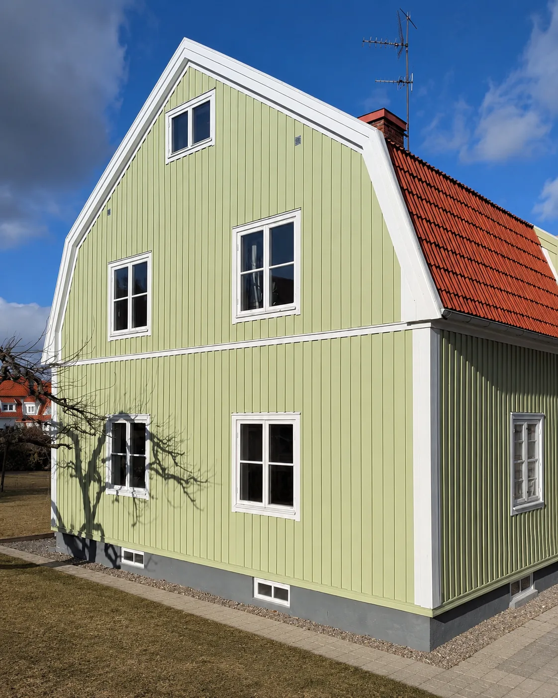 Nymålad ljusgrön stående träpanel med vita knutar och foder på villa i Västerås