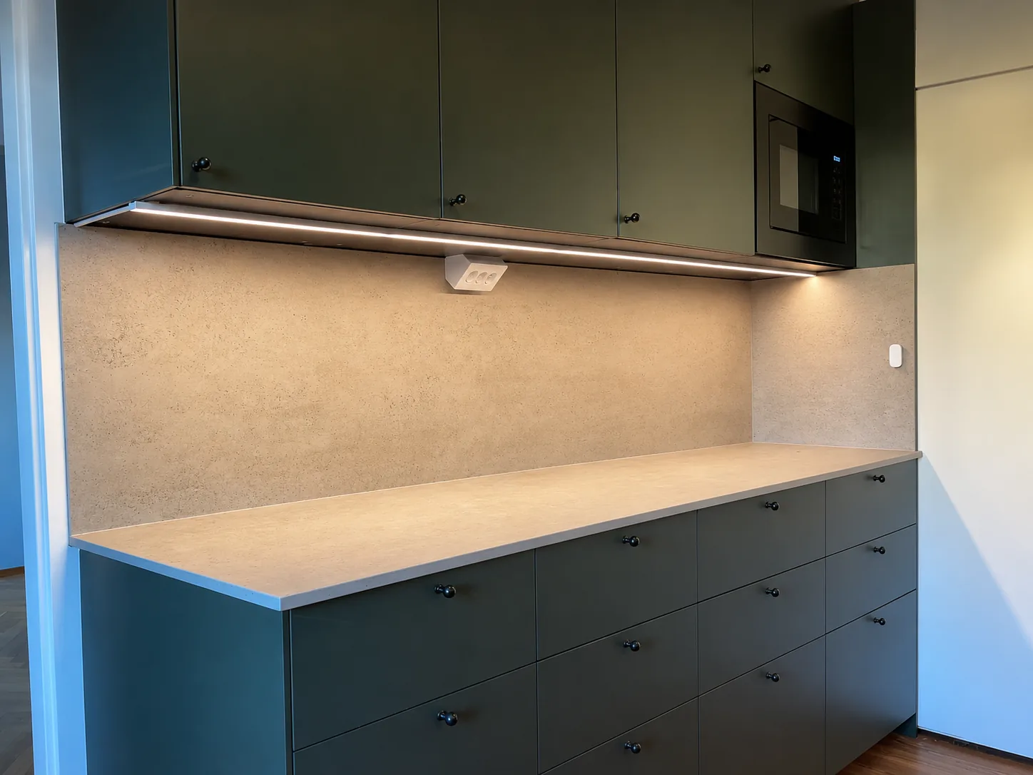 Modern köksrenovering med mörkgröna skåp och stenbänkskiva, utförd i Västerås